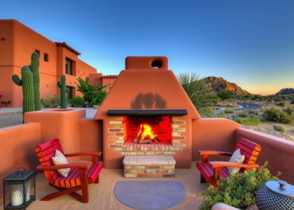 Southwestern adobe outdoor barbecue under desert sky with earthy clay structure, wood-fueled pit, rustic wooden seating, and warm evening ambiance.