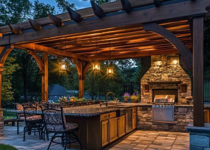 "Cozy outdoor kitchen under a wooden pergola with rustic stone countertops, a handmade wood-burning fireplace, and soft lighting, ideal for evening gatherings."